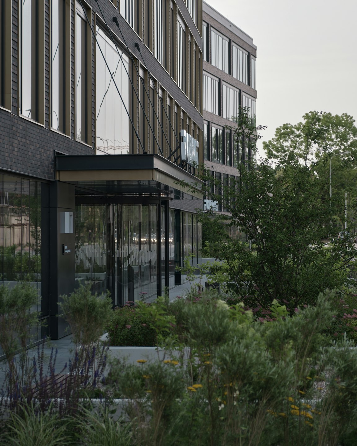 Modern office building with dark brick facade and glass entrance.