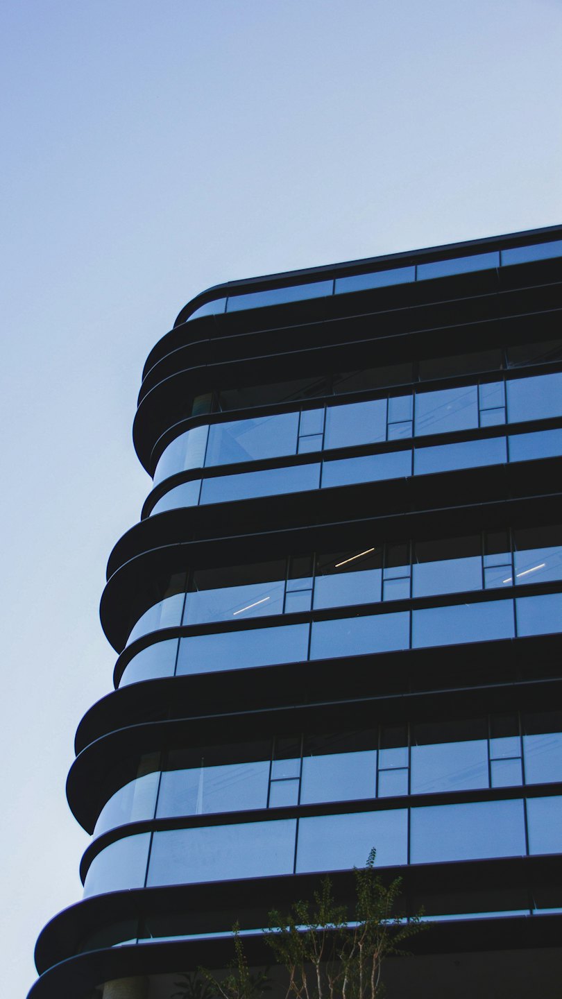 Modern office building with curved glass windows reaches toward the sky.