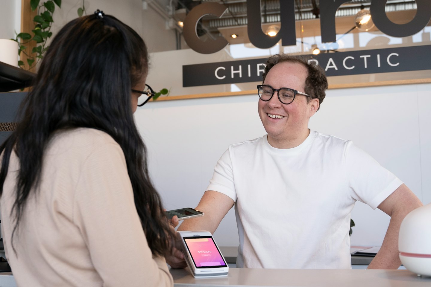 Service professional smiles while assisting customer with payment.