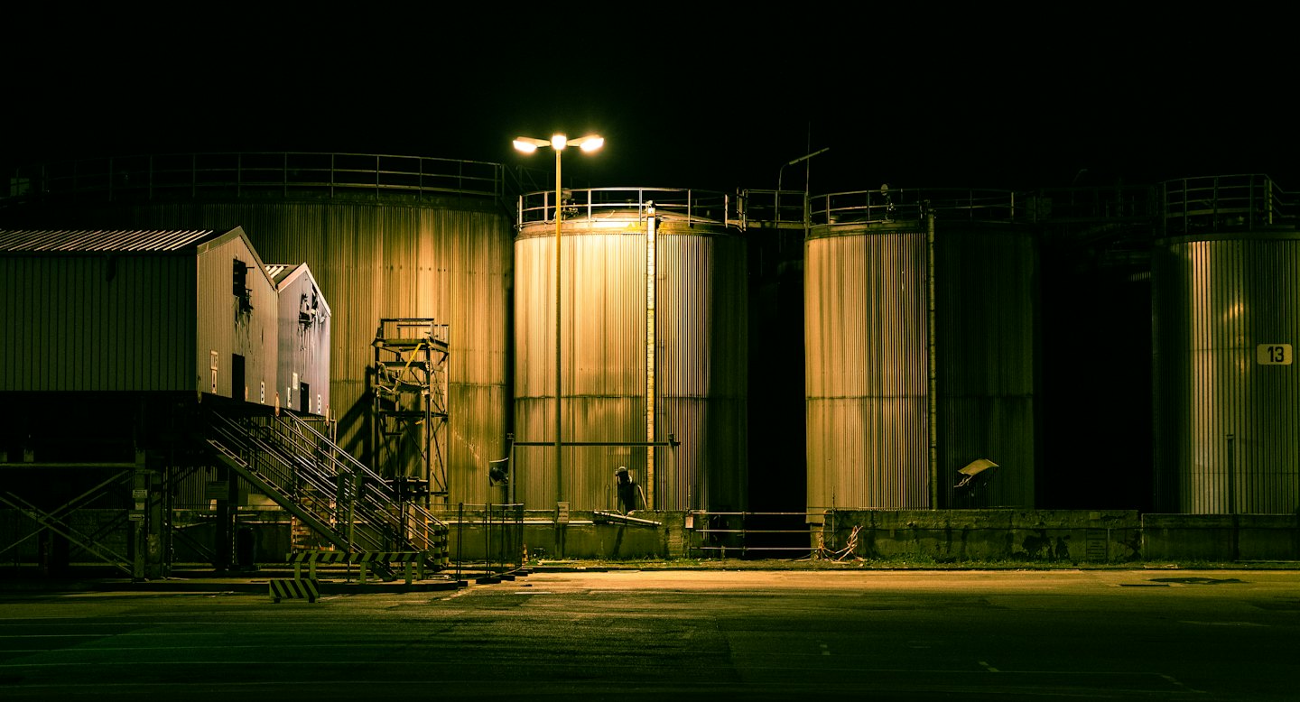 Industrial silos and buildings lit up at night.