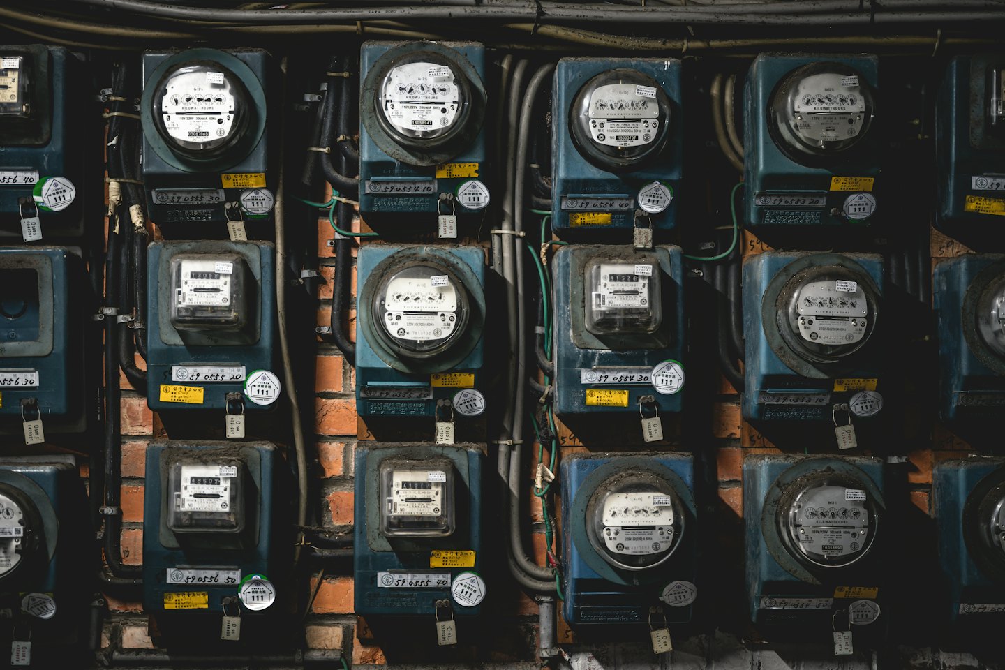 Electrical utility meters mounted on a rustic brick wall.